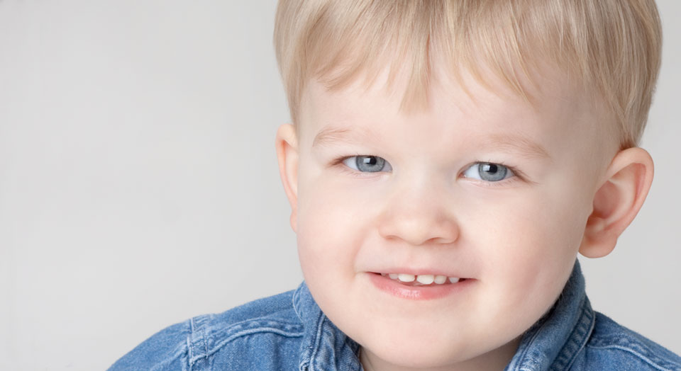 Professional Child Photography, tight headshot of a young boy with a blue denim button up shirt