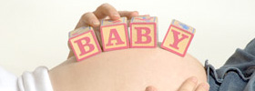 Creative maternity photograph of a pregnant belly with childrens block spelling baby