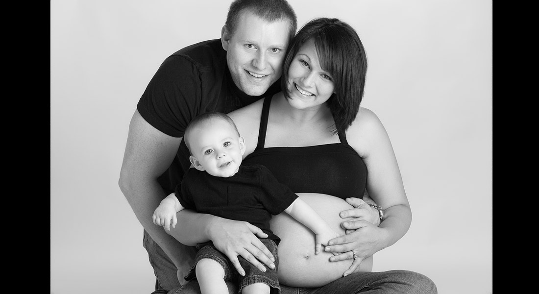 Part family picture and part maternity photography in a black and white studio photograph