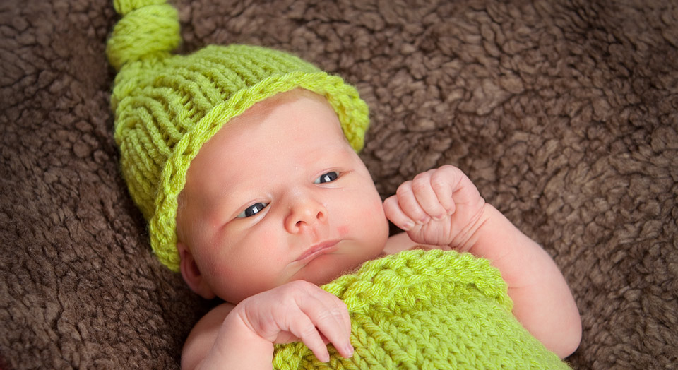 Photography of a Newborn baby wearing a knitted pea-pod like outfit in Grandville, MI